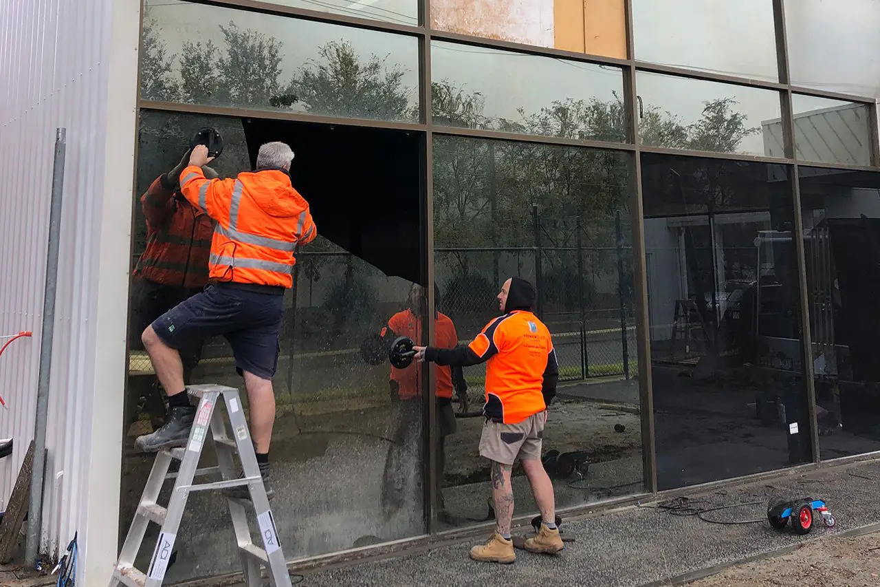 Team of glaziers handling large glass panels during a commercial glazing project in Brooklyn